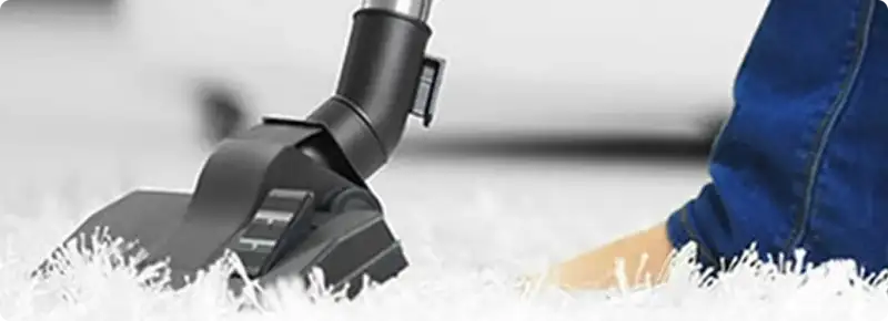 Close-up of a professional vacuuming a white carpet in Otis Orchards.